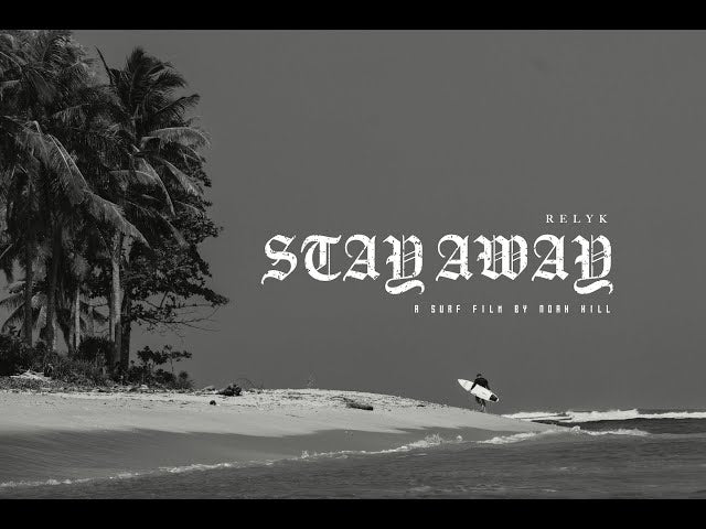 Picture of Stay Away film thumbnail by Noah Hill. Noah walking on tropical beach in distance holding his Rusty Surfboard